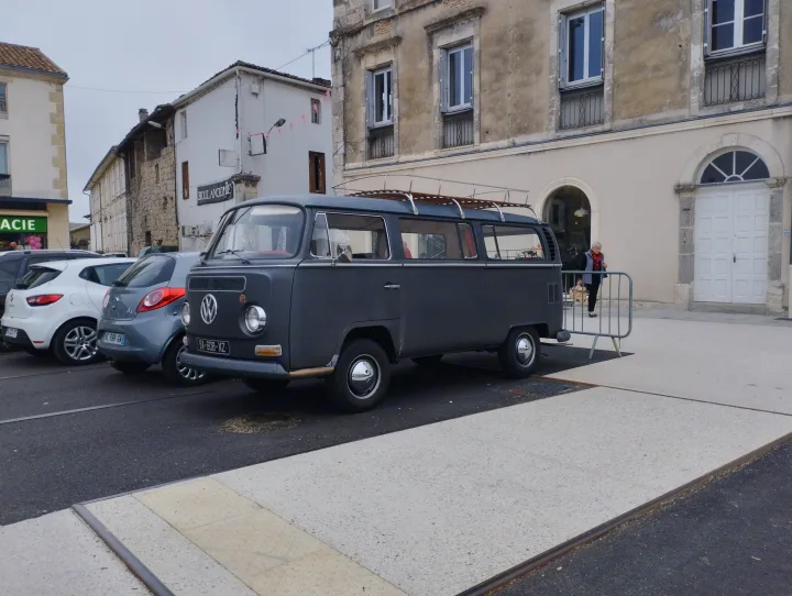 Vintage grey VW bus with roof rack, like a retro RV rental, parked on a European street by a bakery.. Volkswagen Westfalia Combi 1969