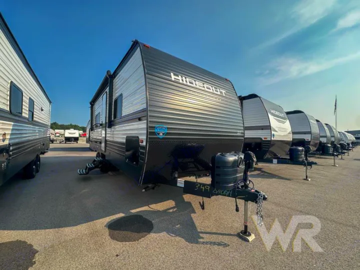 Many dark grey Hideout travel trailers on a sunny RV rental lot, lined up for your next adventure.. Keystone Hideout 240bh 2025