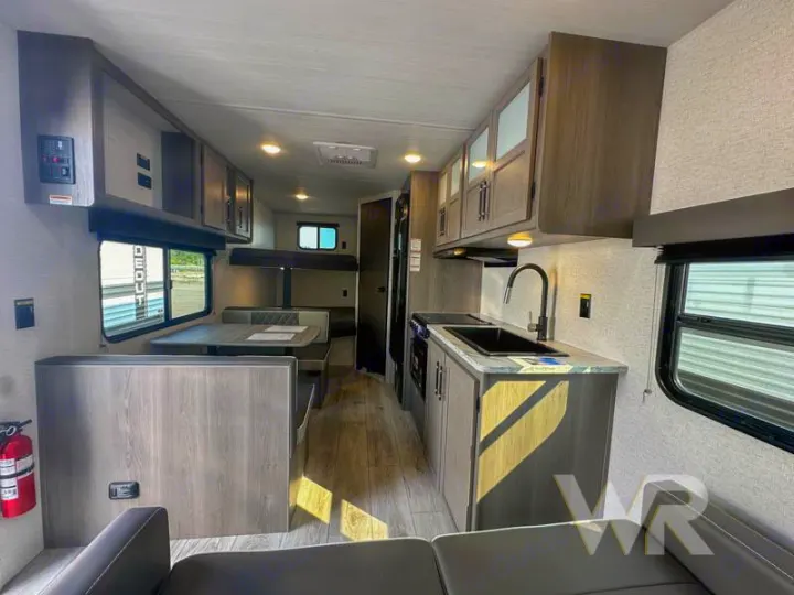 Interior view of an RV rental showing the kitchen with a sink, dinette, and bunk beds, designed for comfortable travel.. Keystone Hideout 240bh 2025