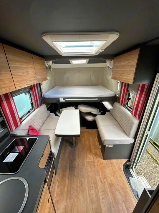 Modern RV rental interior with a cozy kitchen, convertible dining area, and drop-down bed, ideal for road trips.. GlamperRV DBL 2026