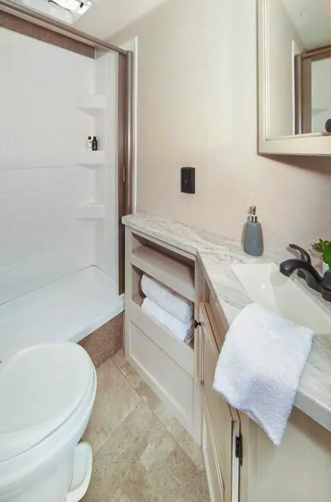 Compact RV rental bathroom features a functional shower, toilet, and vanity with sink, perfect for your adventures.. Starcraft Autumn Ridge 2022