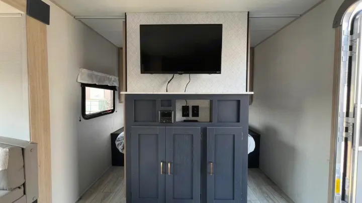 RV rental's interior: TV above a dark gray entertainment console with a stereo system, outlets, and storage.. Prime Time Avenger 2024