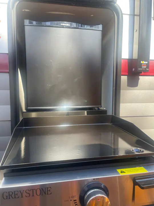An RV rental's outdoor kitchen features a Greystone griddle and Everchill mini-fridge, perfect for convenient outdoor cooking.. Forest River Campsite reserve 27MR 2025