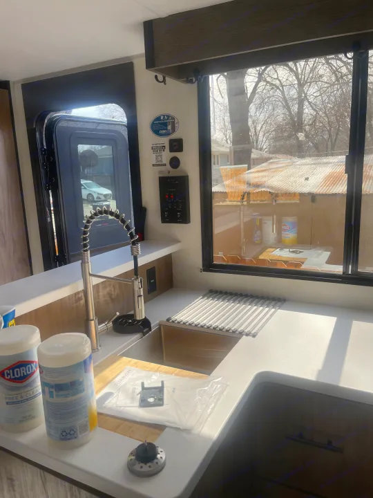Modern RV rental kitchen. Features a large sink with a flexible faucet, drying rack, and functional controls. Clean interior.. Forest River Campsite reserve 27MR 2025