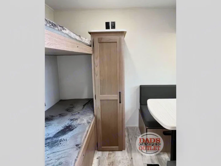 This RV rental interior offers comfort with bunk beds, a tall storage cabinet, and a dinette. Ideal for camper adventures and travel.. Gulf Stream Innsbruck 2024
