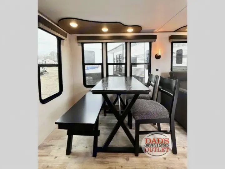 Experience comfort in this RV rental dining area with a sleek dark wood table, bench, and chairs, brightened by large windows.. Gulf Stream Innsbruck 2024
