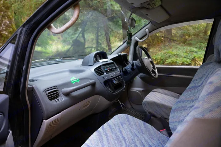 Inside a camper van interior, featuring dashboard, steering wheel, and seats. An rv rental ready for your next nature adventure.. Mitsubishi Delica 2000