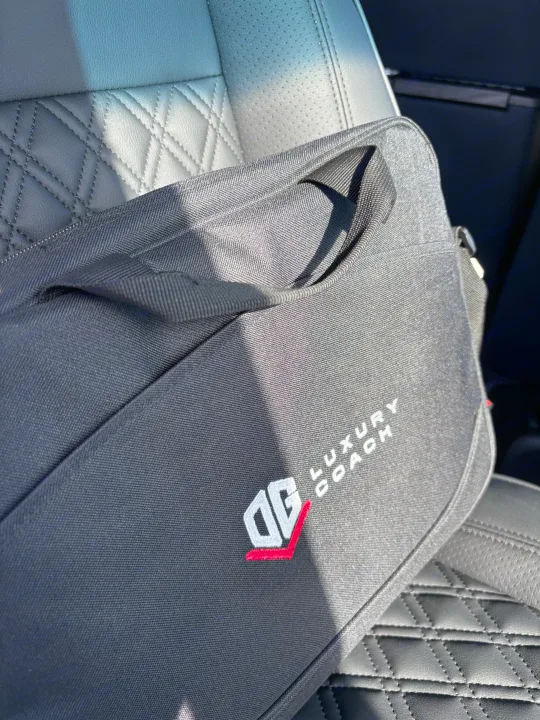 Close-up of a black "Luxury Coach" bag on a quilted leather vehicle seat, perfect for your RV rental journey.. Mercedes-Benz OG Luxury Coach V Cruis 2025
