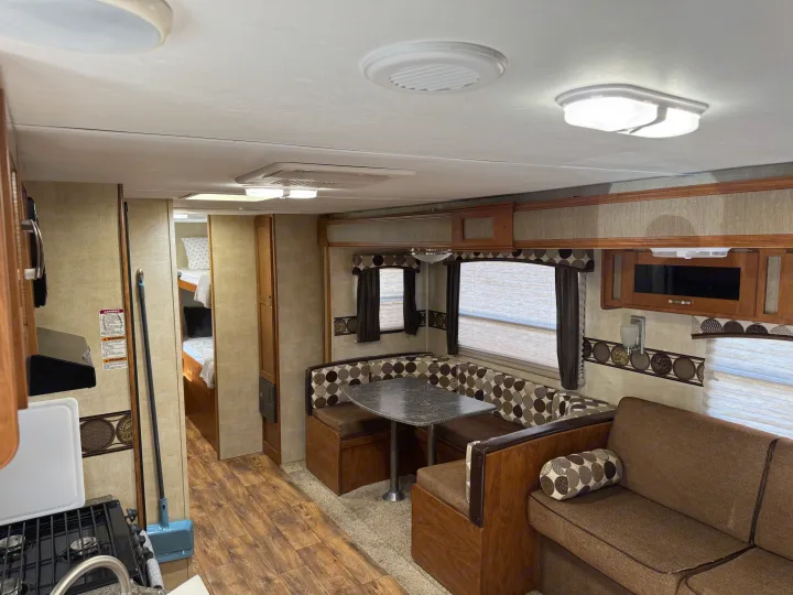 RV rental: Interior view showcasing a well-lit kitchen, booth dinette, sofa, and bunk beds for travelers.. Keystone RV Passport Grand Touring 2014