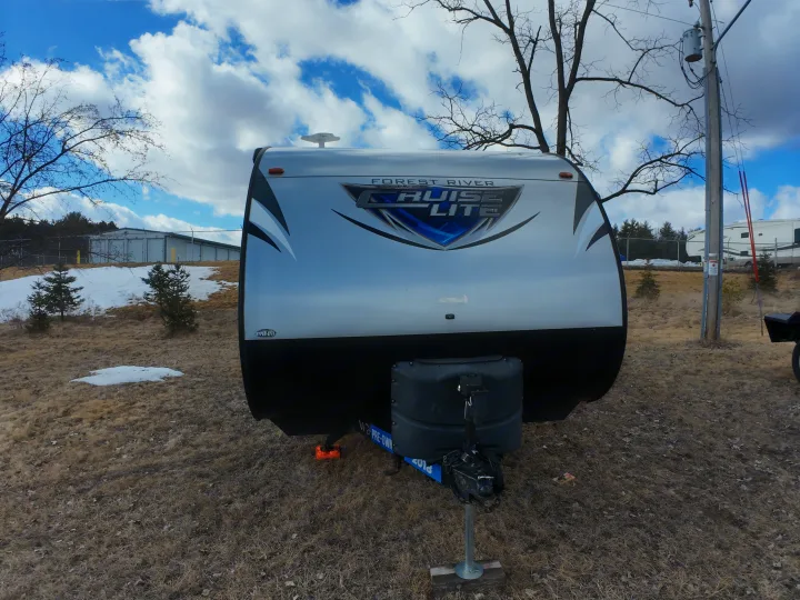 Front view of a silver Forest River Cruise Lite travel trailer, ideal for an RV rental. Parked in a field with melting snow.. Forest River Salem Cruise Lite 2018