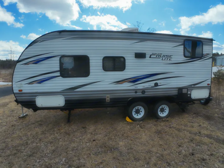 A modern Salem Cruise Lite travel trailer, perfect for an RV rental. This white and gray RV with blue graphics sits on dry ground under a cloudy sky.. Forest River Salem Cruise Lite 2018