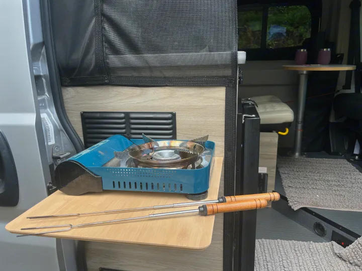 An RV rental's clever pull-out kitchen with a portable gas stove and roasting sticks, ready for camp meals.. Winnebago Solis 2022