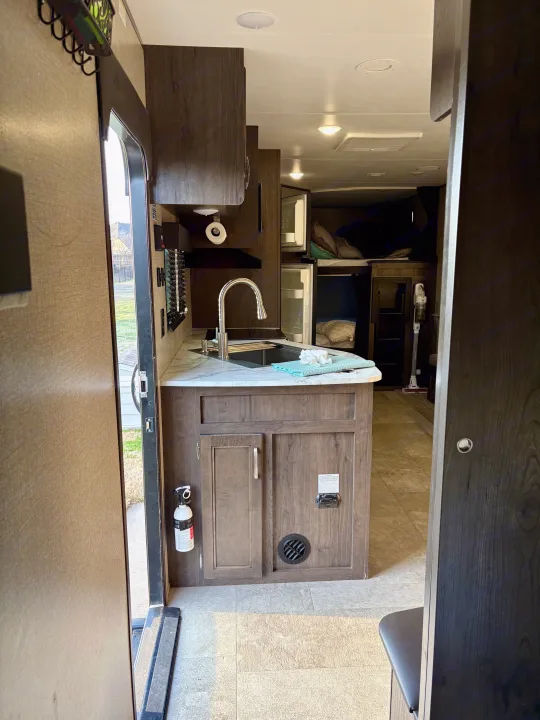 Inside an RV rental: kitchen with sink, fridge, and bunk beds visible from the doorway.. Jayco Jay Flight SLX 2021