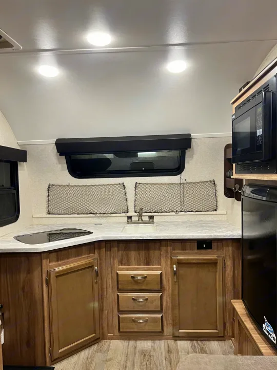 Explore this modern RV rental's compact kitchenette: sink, stovetop, microwave, and fridge. Ideal for on-the-go living.. Jayco Hummingbird 2019