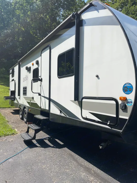 A large, white and gray pet-friendly RV rental is parked outdoors with steps extended, ready for your next adventure.. Forest River Surveyor Legend 2019