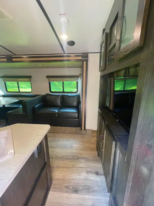 Spacious RV rental living area featuring a comfy sofa, dinette, and entertainment setup. Ideal for travel.. Forest River Surveyor Legend 2019