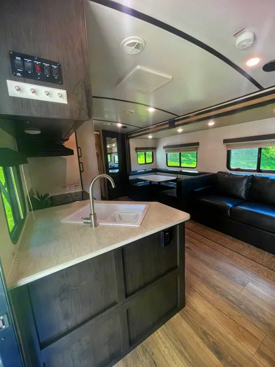 This RV rental showcases a bright interior with a kitchen area, a comfortable dinette, and a spacious sofa, ideal for travel.. Forest River Surveyor Legend 2019