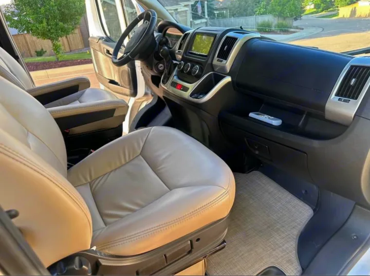 Spacious RV rental front cabin, showcasing light leather seats, a modern dashboard, and steering wheel.. Thor Motor Coach 18T 2022
