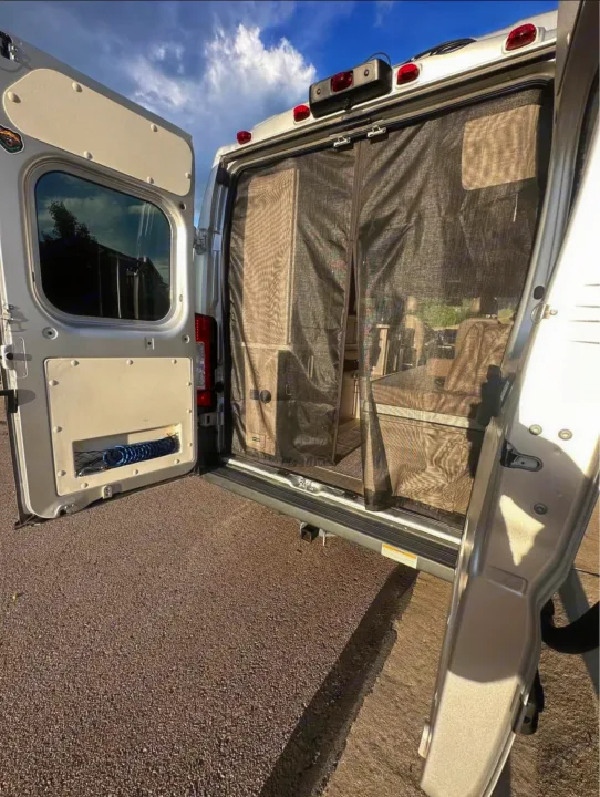 Open rear doors of an RV rental revealing a mesh screen for insect protection and outdoor shower hose, perfect for van life adventures.. Thor Motor Coach 18T 2022