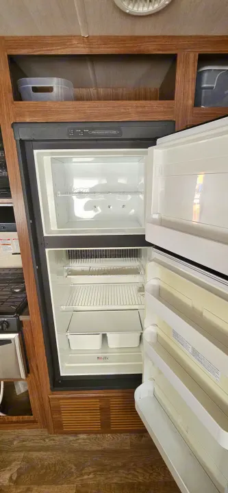 Inside an RV rental, the refrigerator stands open & empty, revealing the freezer, shelves, and crisper drawers. Ready for use.. Heartland RVs Prowler Lynx 2018