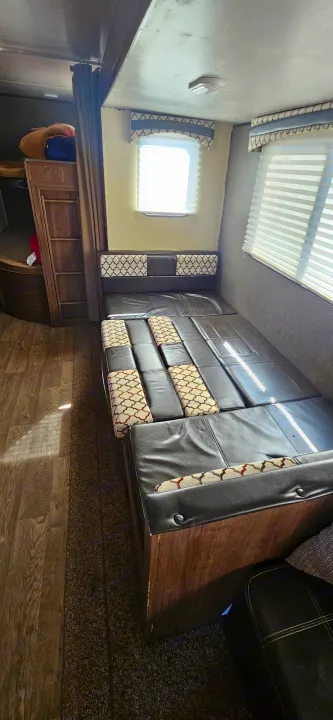 RV rental interior showing a dinette converted to a bed, bunk beds, and windows. A cozy space for travel adventures.. Heartland RVs Prowler Lynx 2018