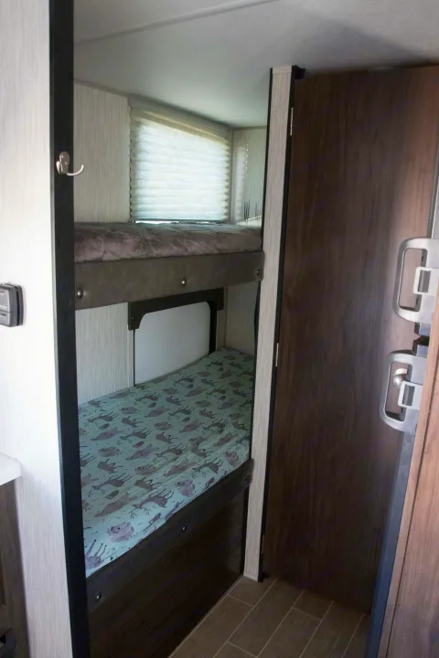 RV rental interior features bunk beds with window and controls, offering cozy sleeping space.. Forest River Cherokee Wolf Pup Black Label 2020