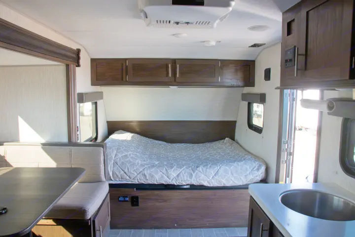 Spacious and modern RV rental interior featuring a cozy bed, dinette, and kitchen area. Perfect for your next adventure.. Forest River Cherokee Wolf Pup Black Label 2020