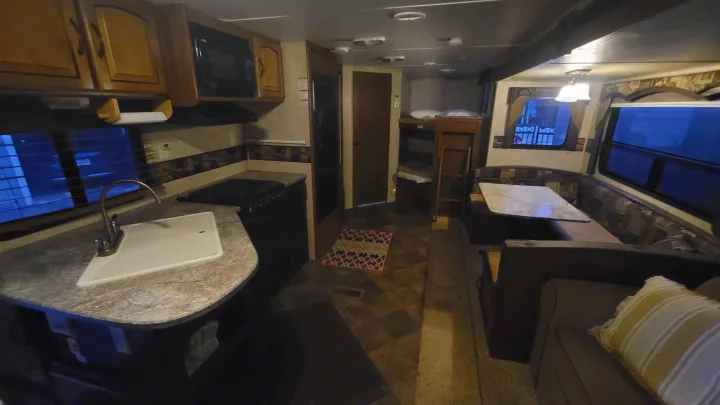 This RV rental interior features a full kitchen, dining area, living space with a sofa, and cozy bunk beds.. Keystone RV Springdale 2012