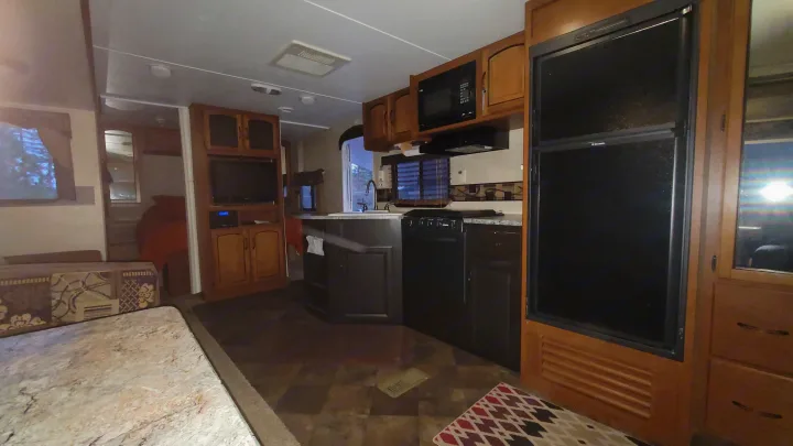 Inside an RV rental: full kitchen with fridge, microwave, stove; cozy living space with sofa and dinette.. Keystone RV Springdale 2012