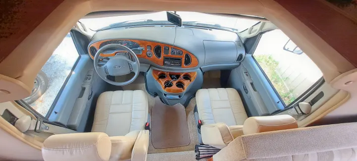 Overhead view of an RV rental's front cabin: dashboard, steering wheel, wood trim, and cream leather seats.. Four Winds Chateau 2007