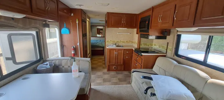 Spacious RV rental interior with kitchen, dining, and living areas, plus a view into the bedroom.. Four Winds Chateau 2007