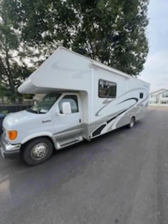 Explore the open road in this white & silver Class C RV, an ideal rv rental for your next travel adventure, parked on asphalt.. Four Winds Chateau 2007