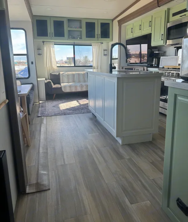 Spacious modern RV rental interior featuring a bright kitchen with light green cabinets and comfortable living area.. Alliance Paradigm 2023