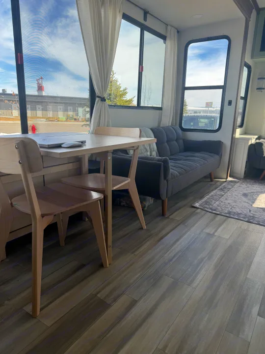 Modern RV rental interior with dining table, laptop, and cozy sofa, offering comfortable mobile living space.. Alliance Paradigm 2023