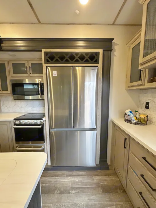 Spacious RV rental kitchen featuring a Samsung fridge, microwave, oven, light cabinetry, and tiled backsplash.. Keystone RV Avalanche 2023