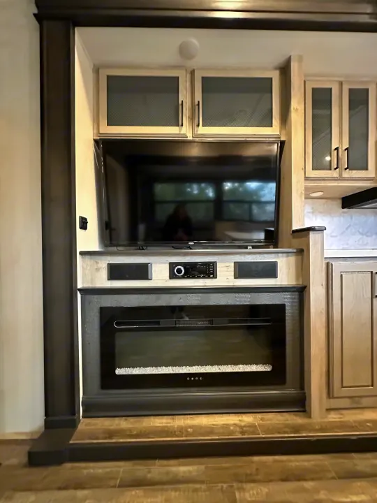 Explore this RV rental's cozy living space! Featuring a modern entertainment unit with TV, audio system, and electric fireplace.. Keystone RV Avalanche 2023