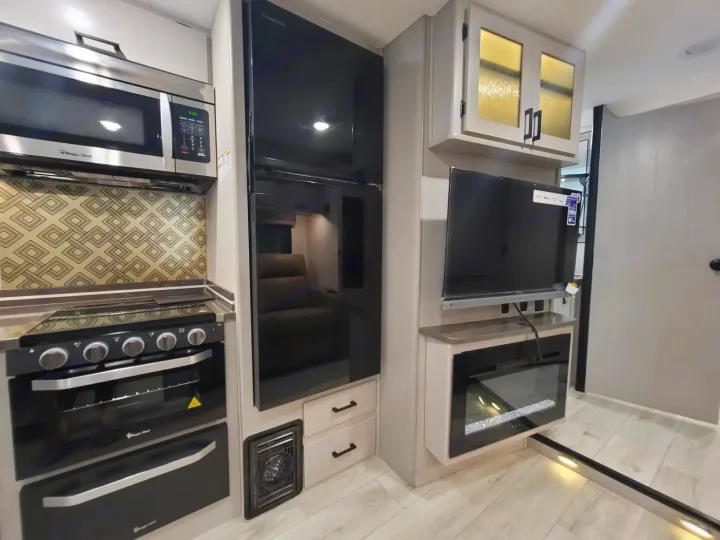 This RV rental boasts a full kitchen with microwave, oven, large fridge, plus a TV and cozy electric fireplace.. Couchmen Entourage 340BH 2025
