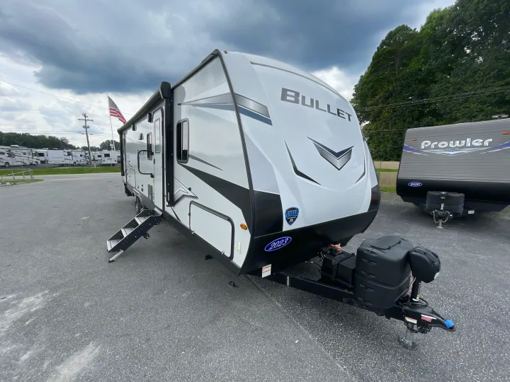 A 2023 Bullet travel trailer, perfect for an RV rental, is parked on a lot under a cloudy sky.. Keystone Bullet 2023