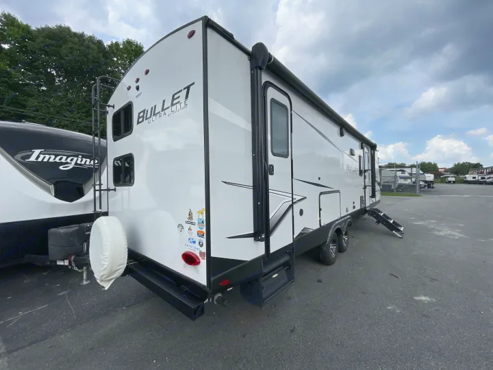 White Keystone Bullet travel trailer RV for rv rental, parked in an outdoor lot with steps extended.. Keystone Bullet 2023
