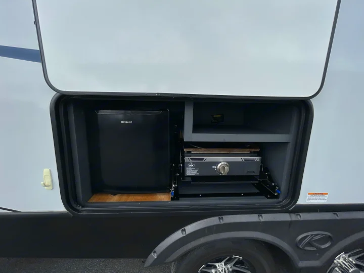 An RV rental's outdoor kitchen features a Hotpoint mini-fridge and a Capital Griddle, perfect for convenient outdoor cooking.. Keystone Bullet 2023