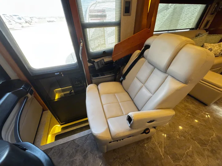 View inside an RV rental showing a cream captain's chair, tiled floor, and entrance steps with outdoor view.. New Aire New Aire Motorhome 2020