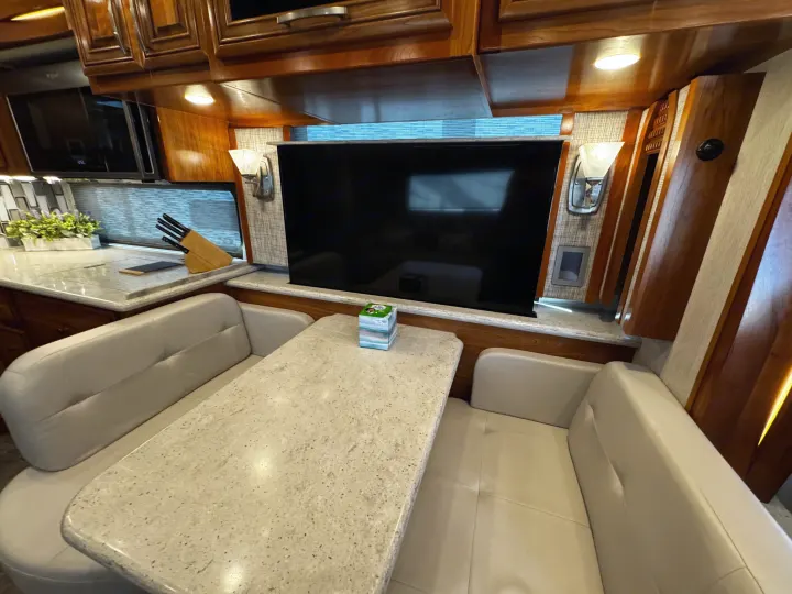 RV rental interior: A comfortable dinette with a large TV and a well-appointed kitchen, perfect for travel.. New Aire New Aire Motorhome 2020