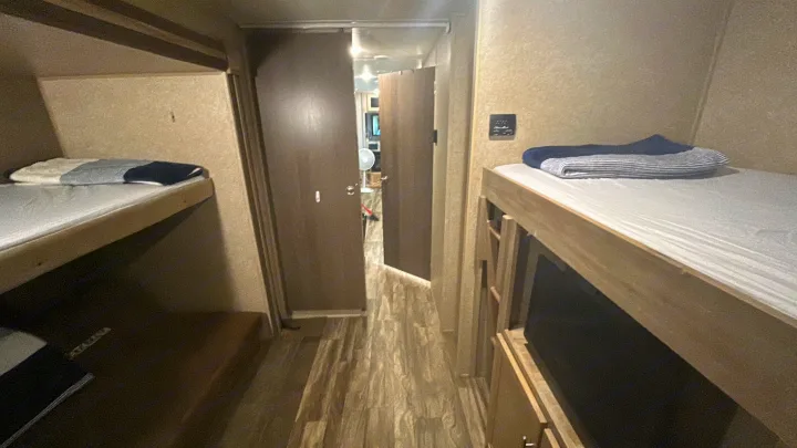 RV rental interior: narrow hallway with bunk beds on both sides, providing compact sleeping in this travel camper.. Coachmen Catalina 2019