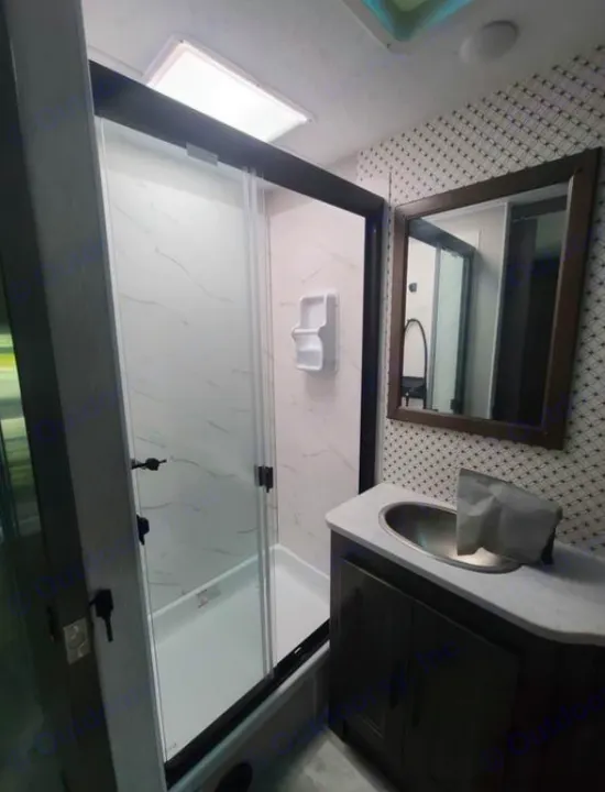 RV rental bathroom: bright shower with glass doors, dark wood vanity, and patterned accent wall.. Coachmen Mirada 2024