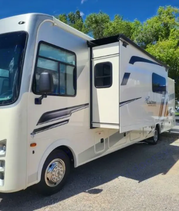 Spacious white Class A RV rental (Coachmen Mirada) with slide-out extended, parked on gravel. Ready for adventure.. Coachmen Mirada 2024