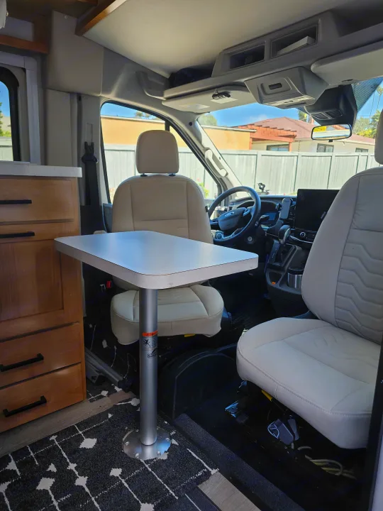 Spacious RV rental interior: front cabin with swiveling seats and a table for dining/workspace.. Forest River Coachmen Beyond 2023