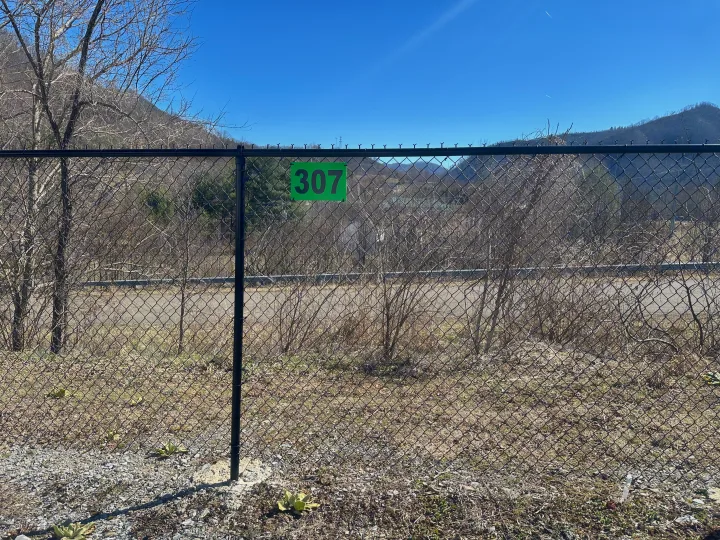 Site 307: chain-link fence, mountain backdrop. Consider for your next rv rental.. Ozark Lite 2021