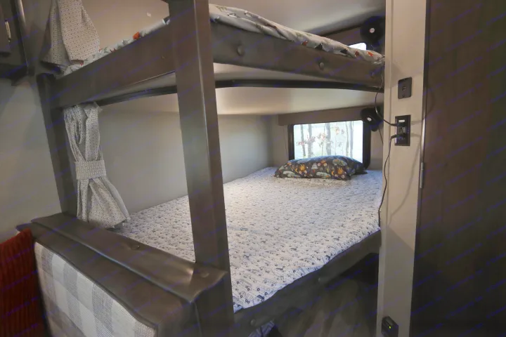 Cozy RV rental bunk beds, perfect for family adventures. Features vehicle-patterned sheets & window views.. Grand Design Transcend Xplor 2020