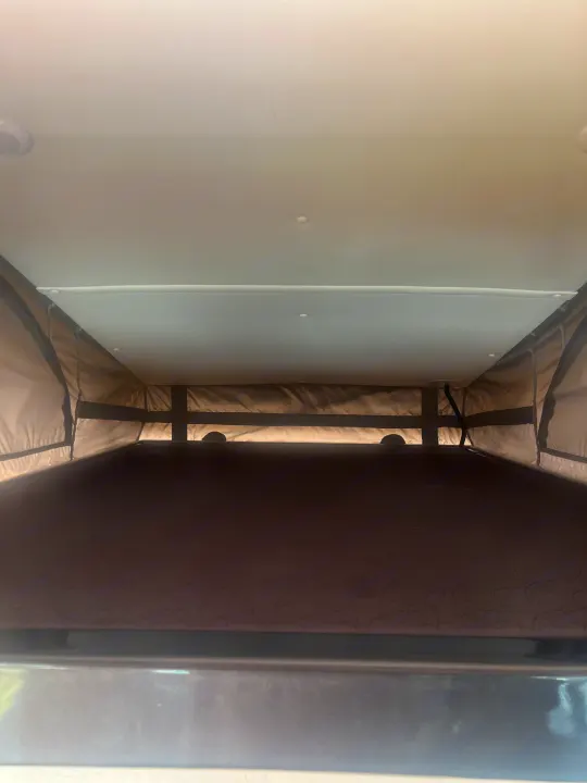 Inside an RV rental pop-top camper: a view of the elevated sleeping area with its bed, fabric walls, and ceiling.. Pleasure-Way Pleasure-Way Class B 2022