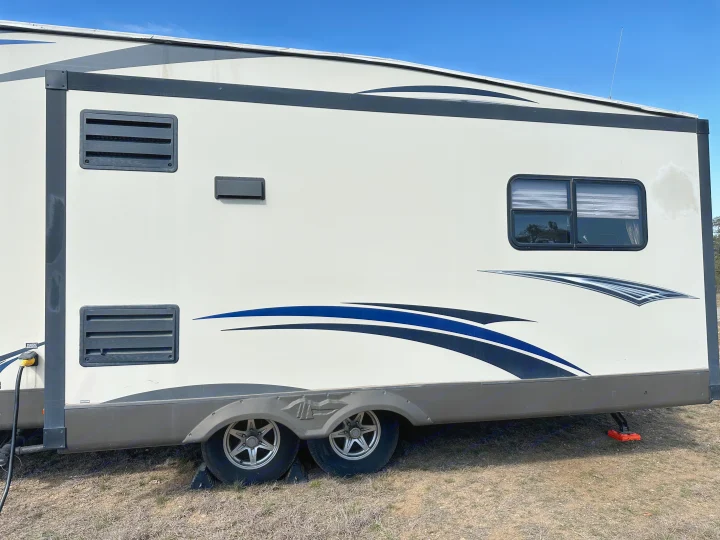 Side view of a white rv rental travel trailer with blue and black graphics, parked and leveled, ready for your next outdoor adventure.. Forest River Salem Hemisphere Lite 2015